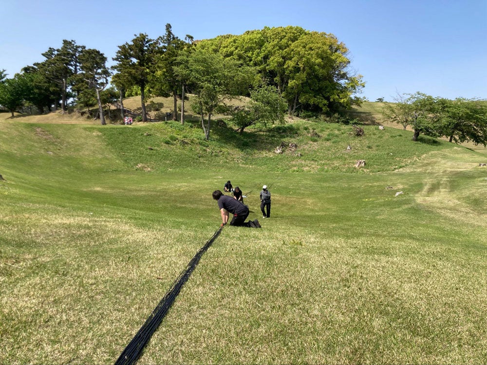 広大なゴルフ場で、人力でケーブルを敷設
