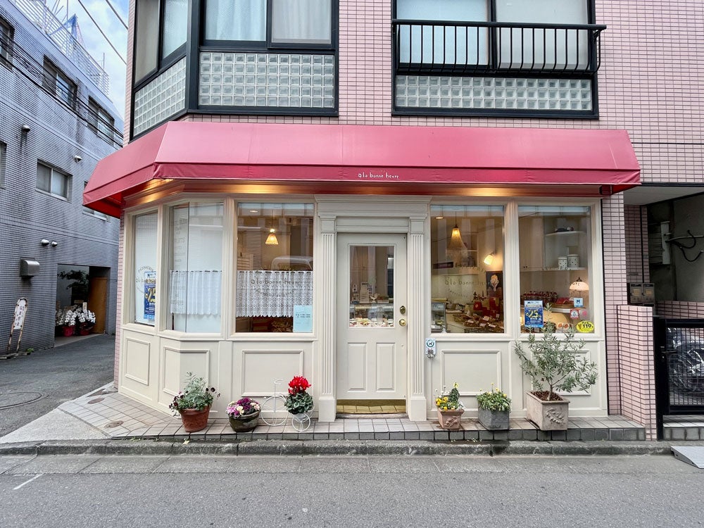 赤いひさしと白壁が可愛らしい店舗外観